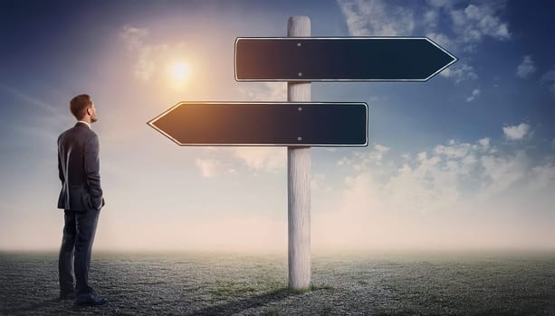 Businessman in suit standing on a empty field looking at a wooden signpost with two blank directional arrows pointing left and right sides. Business decision and difficult choice concept
