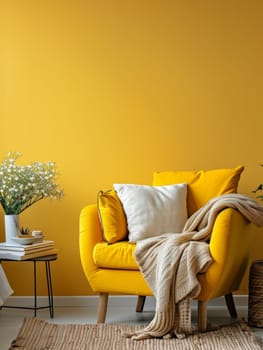 A cozy yellow armchair and a soft blanket invite relaxation beside a stack of books and fresh flowers