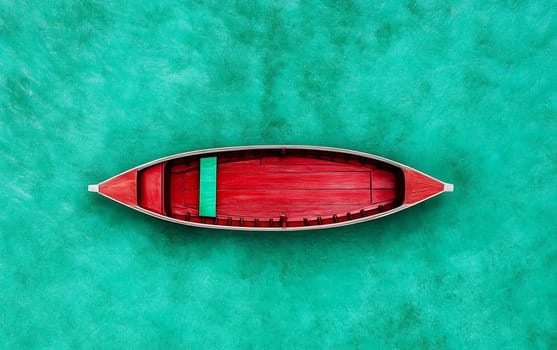 Red boat on turquoise ocean water - top view of vibrant wooden vessel.