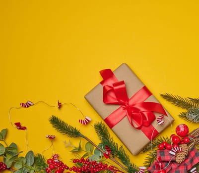 Christmas background, wrapped gift in brown paper and red silk ribbon, top view. Copy space