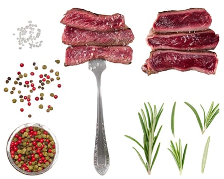 Juicy slices of beef, sprinkled with coarse salt, are skewered on a fork. A mixture of multi-colored black, red, green peppercorns, sprigs of fresh rosemary and large crystals of salt