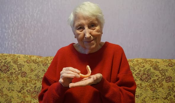 flexible nylon denture on senior female hands. Removable dentures flexible, devoid of nylon, hypoallergenic exempt from monomer