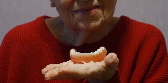 flexible nylon denture on senior female hands. Removable dentures flexible, devoid of nylon, hypoallergenic exempt from monomer