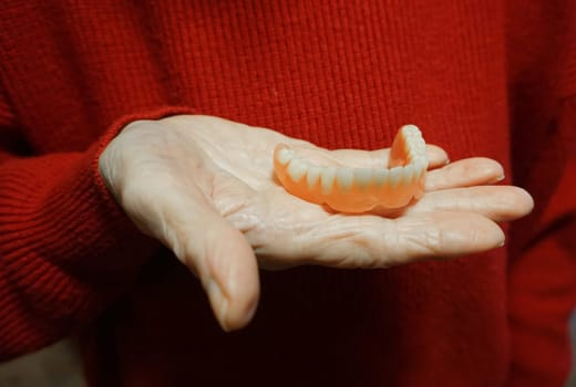 flexible nylon denture on senior female hands. Removable dentures flexible, devoid of nylon, hypoallergenic exempt from monomer