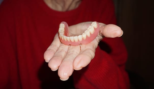 flexible nylon denture on senior female hands. Removable dentures flexible, devoid of nylon, hypoallergenic exempt from monomer