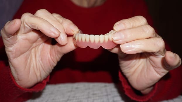 flexible nylon denture on senior female hands. Removable dentures flexible, devoid of nylon, hypoallergenic exempt from monomer