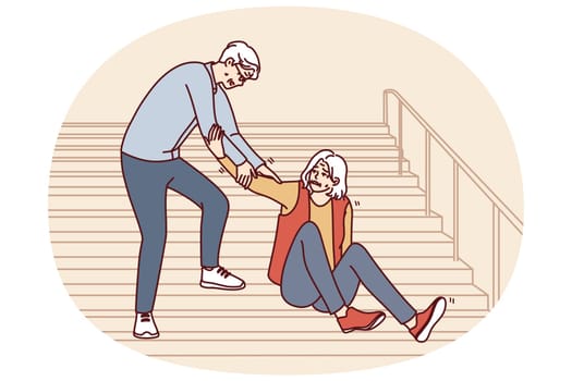 Elderly man helps fallen old woman up while descending street staircase. Gray-haired caring grandfather provides first aid to grandmother who has fallen on walk and descending stairs