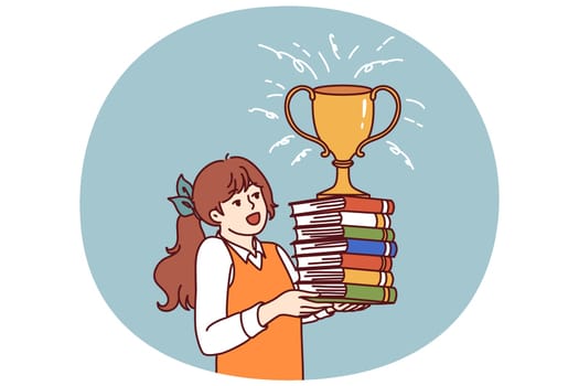 Schoolgirl with books and cup for winning olympiad rejoices at good marks for test. Child prodigy girl with golden cup of winner of olympiad enjoys prize of best elementary school student