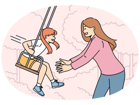 Mom takes daughter on swing in park and enjoys relaxing with child in fresh air. Happy family of woman with little girl having good summer vacation or weekend in backyard with swing