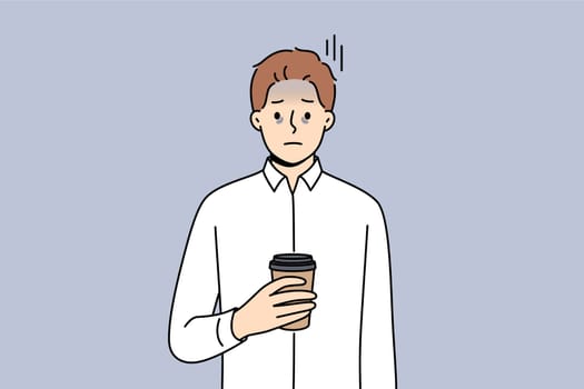 Tired business man suffering from exhaustion and burnout and holding paper cup of coffee in hands. Problems exhaustion among office employee experiencing health difficulties due to constant overtime