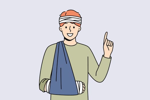 Injured man with bandaged head and hand pointing with finger up recommending getting health insurance. Happy young sick guy rejoices having medical insurance after fall or car accident