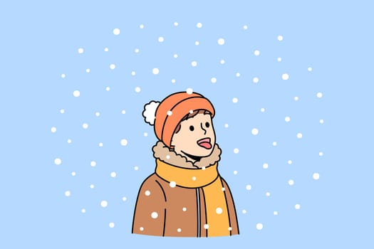 Boy opens mouth and eating snow, enjoying winter weather and new year mood. Christmas portrait of small child in scarf and warm hat, rejoicing with first snow or onset of winter holidays