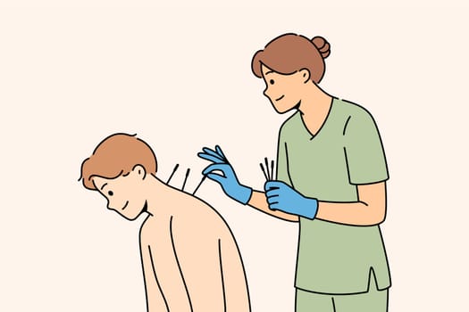 Acupuncture procedure from eastern alternative medicine for man sitting near woman doctor. Girl gives acupuncture to patient to combat pain in spine or osteochondrosis causing poor posture.