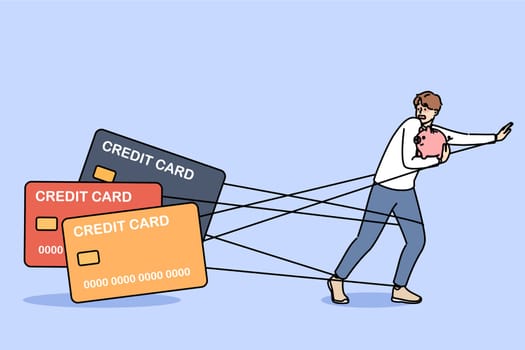 Man debtor has become hostage to loans and is running away from bank cards holding piggy bank in hands. Problems of credit dependence are caused by lack of freedom of guy who owes money