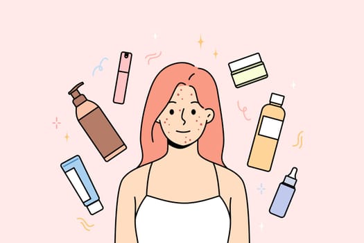Woman with freckles and pimples on face smiles, stands among jars of creams and gels or shampoos. Cosmetology products around girls who want to get rid of acne and freckles on skin.
