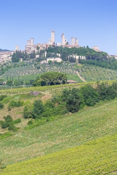 San Gimignano village, Italy - green countryside, blue sky, hill panorama with town and towers