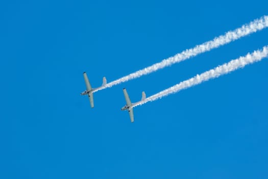 Stunt aerobatic plane performing stunts in blue sky with smoke trail. Concept of teamwork, collaboration, coordination, trust, precision, difficulty, challenge, speed, synergy