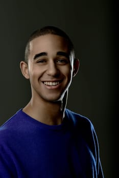 Portrait of a cheerful young man smiling and looking at the camera against a dark background. Portrait