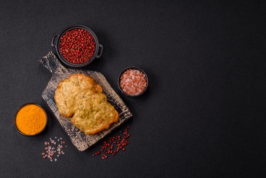 Delicious fried pork or chicken chops breaded with salt and spices on a dark concrete background