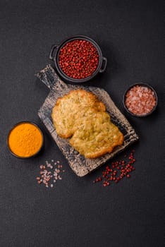 Delicious fried pork or chicken chops breaded with salt and spices on a dark concrete background