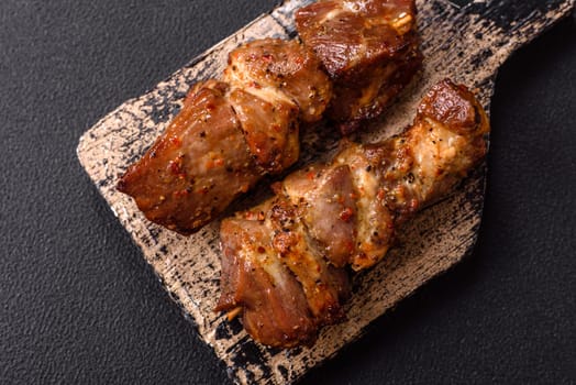 Delicious grilled chicken, turkey or pork skewers with salt, spices and herbs on a fire on a dark concrete background