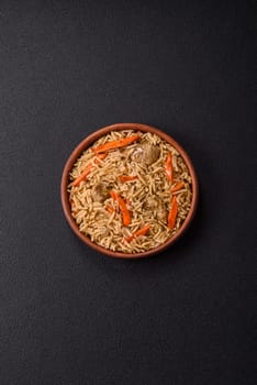 Delicious fresh pilaf with rice, carrots, meat, onions, spices and berries on a ceramic plate on a dark concrete background