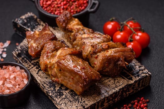Delicious grilled chicken, turkey or pork skewers with salt, spices and herbs on a fire on a dark concrete background