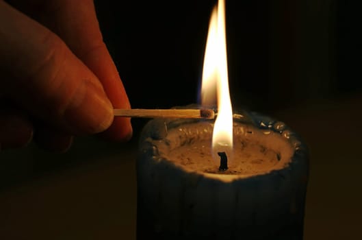 A woman lights a candle in the dark