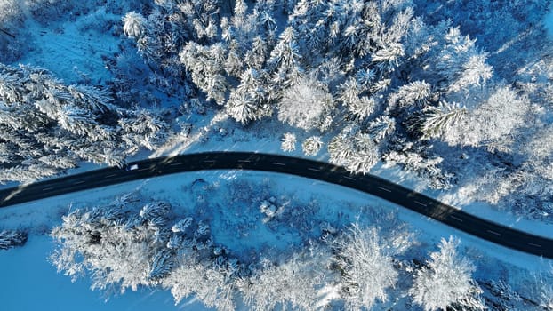 Drone shot of a winding road in winter with a car