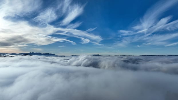 Drone shot in winter with fog in the valley and sun in the mountains