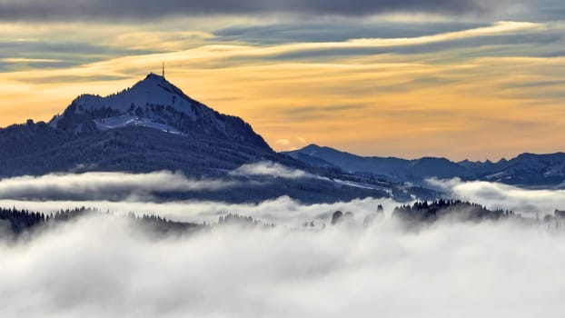 Drone shot in winter with fog in the valley and sun in the mountains at sunset