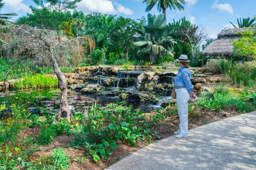 A woman enjoying a view of a beatuful cascade and a pond in a park in Florida