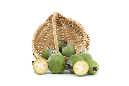 Green feijoa fruits overflow from a woven basket, showcasing their fresh and vibrant look. The arrangement highlights the natural textures and appealing colors of this tropical fruit.