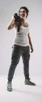 Young woman photographer smiling while holding her camera over her shoulder, embodying her passion for photography and visual storytelling in a joyful, confident pose