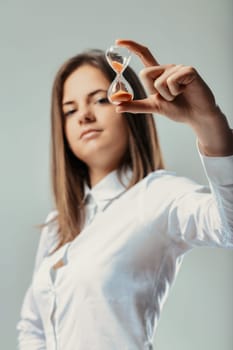 Young businesswoman holding a small hourglass, emphasizing time management's role in professional settings and encouraging reflection on deadlines and efficiency