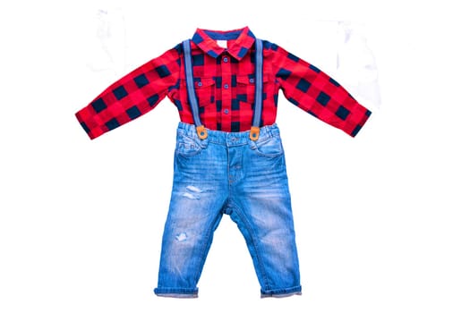 Jeans isolated. Trendy stylish denim pant or trousers for child boy with blue striped suspenders and a red checkered shirt isolated on a white background. Clipping path. Childrens summer fashion.