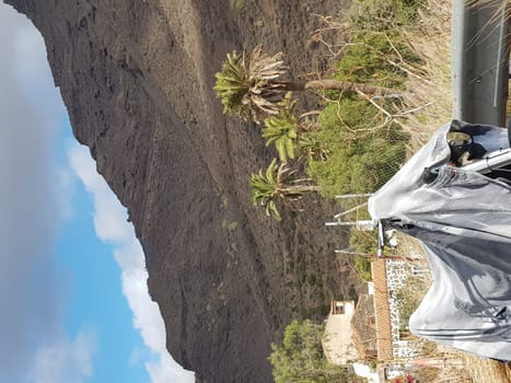 CRAN CANARIA, MELONERAS, SPAIN - 15. NOVEMBER 2019: Cran Canaria, Meloneras, Spain - 15. November 2019: Old motorcycle stands covered under a motorcycle tarpaulin on the roadside during sunset
