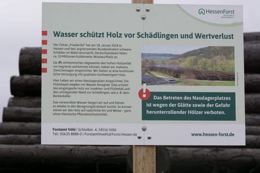 BAD WILDUNGEN, HESSEN, GERMANY - OKTOBER 30, 2018: Bad Wildungen, Hessen, Germany - Oktober 30, 2018: Wood yard business. Wood stacked outdoors. Concept forest industry environment. Felled tree trunks are sprayed with water to protect them against wood pests