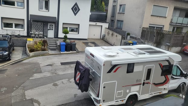 HEILIGENHAUS, NRW, GERMANY - AUGUST 06, 2022: Heiligenhaus, Nrw, Germany - August 06, 2022: Camping and tourism theme. Modern camper van with solar panels installed staying on the cobblestone driveway waiting for a new destination. aerial view