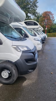 A row of pristine white campervans parked in a lot, ready for adventure.