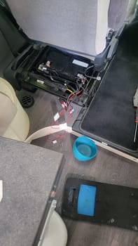 working on the electrical system of a car, with wires, a battery, and tools visible.