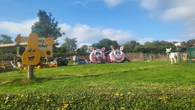 A picturesque farm scene with hay bale pigs, pumpkins, and a sign welcoming visitors.