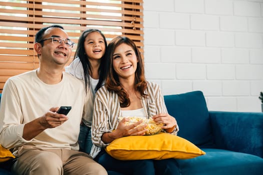 In warm atmosphere of their house smiling family bonds while watching TV with popcorn. father mother son daughter and schoolgirl radiate happiness epitomizing togetherness and candid enjoyment.