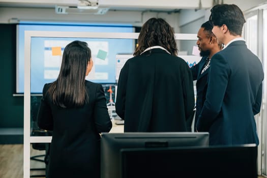 Colleagues gather for a back meeting, showcasing teamwork and brainstorming, as they discuss strategies on the glass wall. A diverse community working towards goals, led by a CEO.