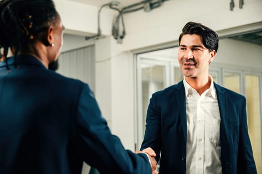 Colleagues celebrate their achievement with a handshake in an office. Business professionals, including executives and lawyers, mark a successful partnership.Teamwork