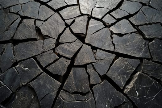 Close-up of cracked dark stone surface with irregular fragments, ideal for backgrounds, textures, and design elements.