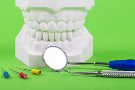 white denture mold with dentist tools on green background