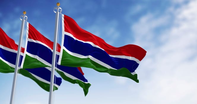 National flags of the Gambia waving in the wind on a clear day. Three horizontal red, blue, and green bands, separated by two narrow white bands. 3d illustration render. Fluttering fabric