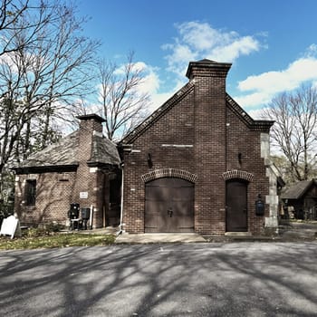 Historic brick building with twin chimneys and blue sky in autumn.