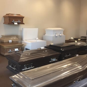Variety of elegant caskets displayed in funeral services showroom.